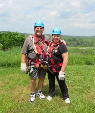 two people posing with ziplining gear on