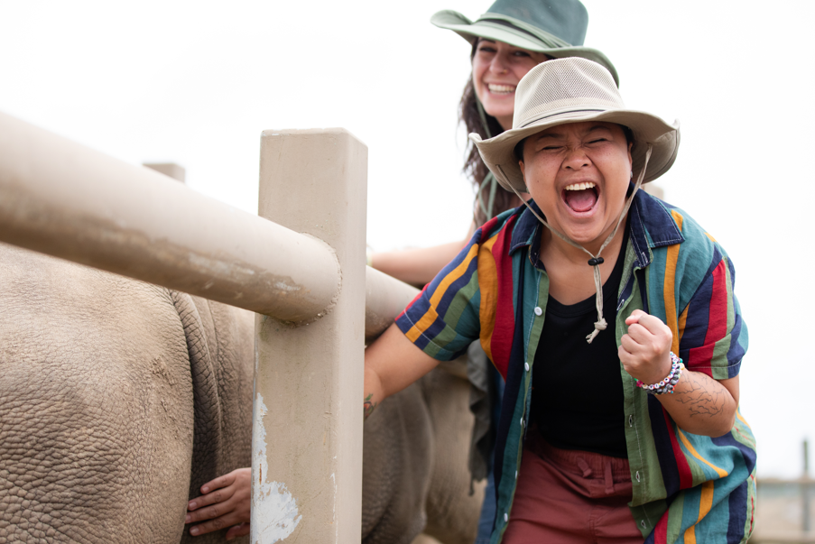 Guest at The Wilds smiling and touching a rhino