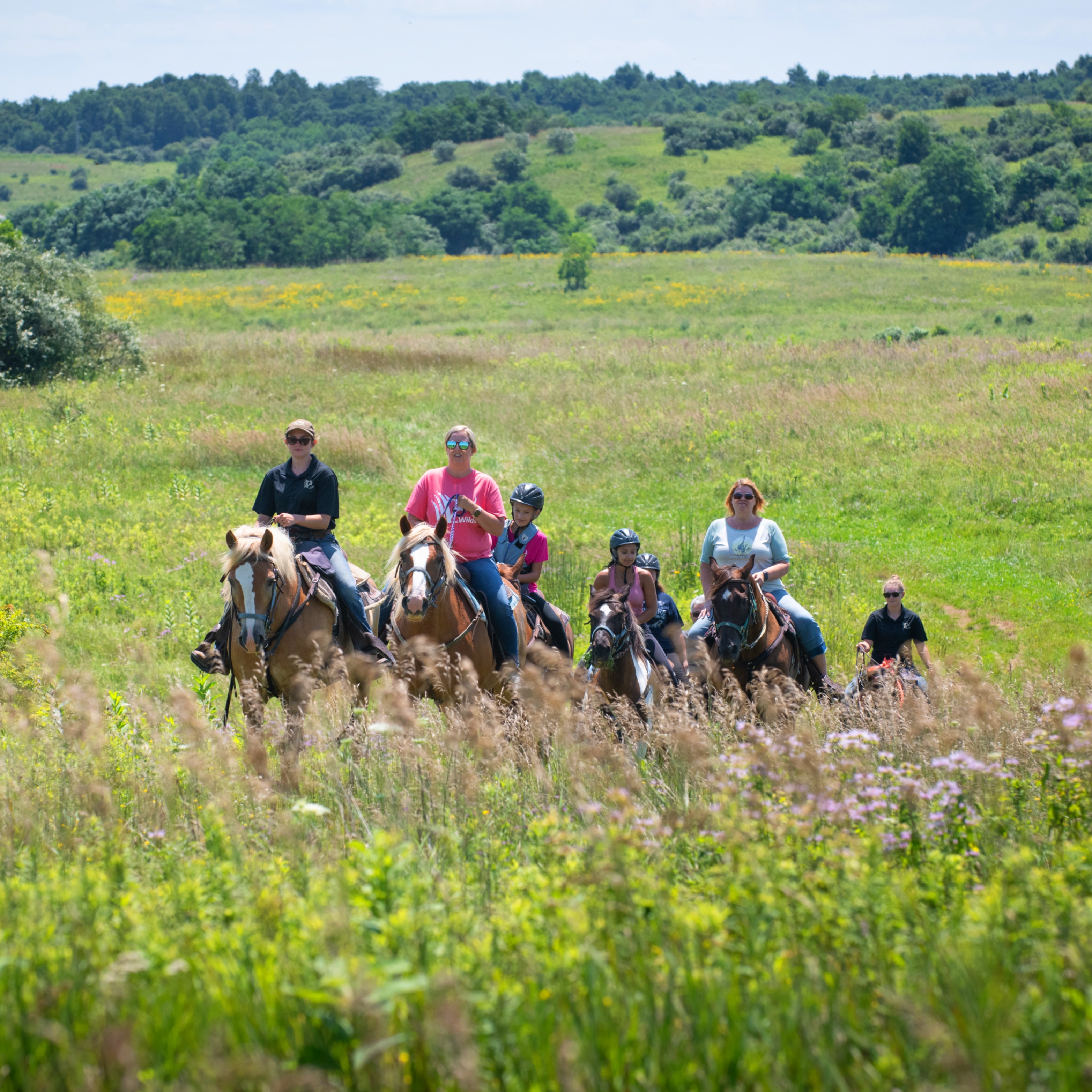 family horseback riding in pasture