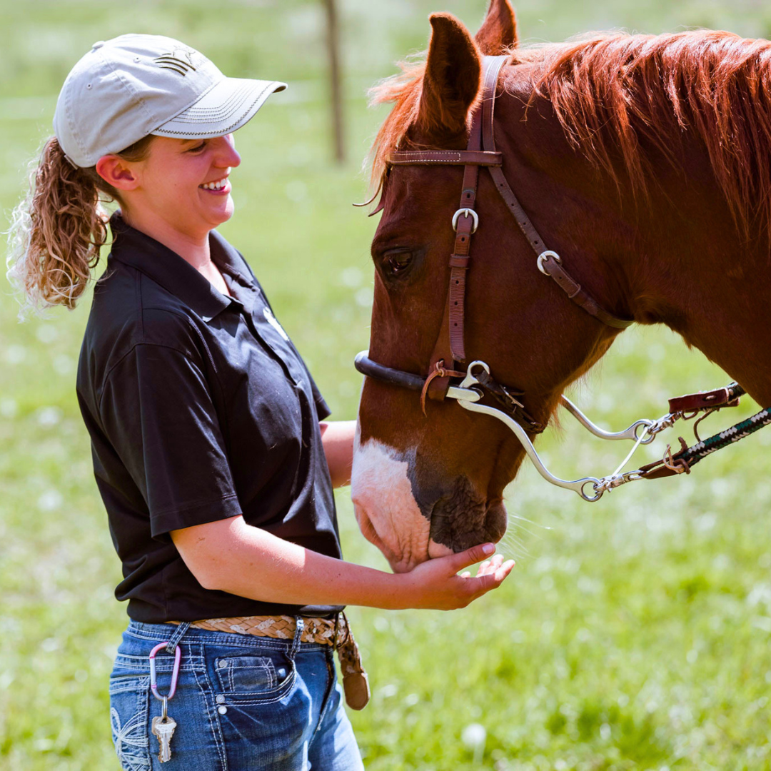 woman smiling while looking at horse