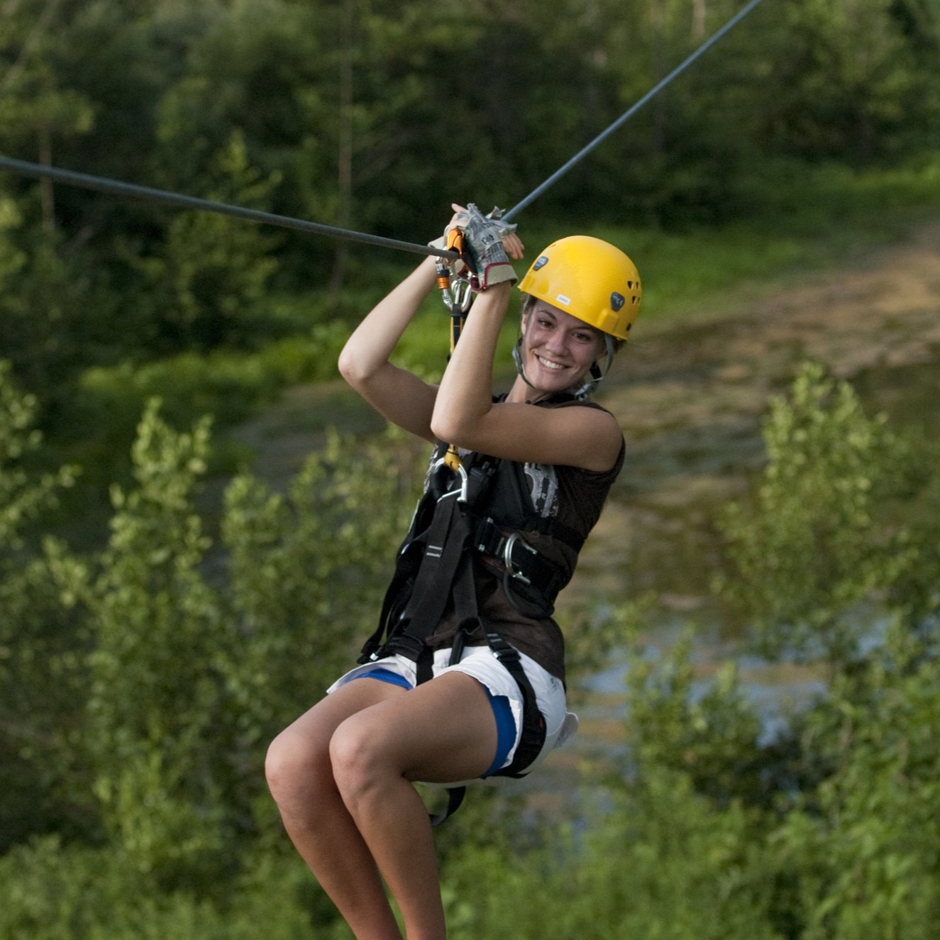 woman ziplining through the forest