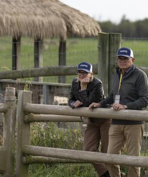 Two guests at The Wilds leaning on wooden fence